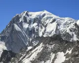 Majestatyczny, ośnieżony szczyt, gdzie jest Mont Blanc, góruje nad skalistym, pokrytym śniegiem zboczem.