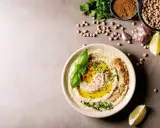 Pyszny hummus z oliwą, ziołami i bazylią. Obok ciecierzyca, czosnek, cytryna i chleb. Czy można mrozić hummus? Tak, można go mrozić.