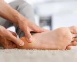 Main d'un homme massant son talon, soulageant une douleur liée à une épine calcanéenne prise en charge.