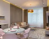 Nowoczesny salon z aneksem kuchennym po generalnym remoncie mieszkania 50m2. Jasne kolory, welurowa sofa i różowe krzesła tworzą przytulną atmosferę.