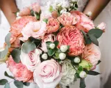 En vacker bukett med rosa rosor, nejlikor och eukalyptus. Perfekta blommor till dukning för ett romantiskt bröllop.