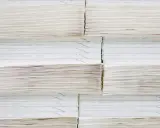 Grandes pilas de papel offset, algunas con finas líneas impresas, apiladas ordenadamente en un almacén.