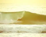Surfer reitet eine Welle im goldenen Licht. Ein perfekter Moment beim el palmar surfen.