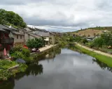 Casas de piedra a orillas del **río de Onor**, con vegetación exuberante y un cielo nublado.