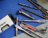 Niveau à bulle et divers outils du maçon, incluant des forets et des mèches, prêts pour le travail.