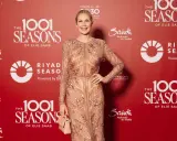 A woman in a sparkling celio saab gown poses at an event with "1001 Seasons of Elie Saab" branding.