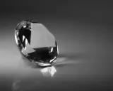 Un diamante sfaccettato riflette la luce su una superficie lucida. Il suo fascino misterioso evoca il significato dei diamanti neri: forza e resilienza.