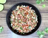 Świeże, kolorowe pico de gallo w czarnej misce, z limonkami i kolendrą na drewnianym tle.