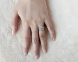 Mano femminile con due anelli scintillanti, uno con un grande diamante centrale e l'altro con pietre più piccole. Il dito anulare è il posto tradizionale dove si mette l'anello di fidanzamento donna.