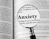 Lupa powiększa definicję "Anxiety" w książce, opisując uczucie niepokoju, które może prowadzić do fobi.