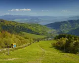 Widok na zielone beskid mały szczyty, jezioro i miasteczko. Kolejka krzesełkowa wjeżdża na górę.