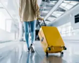 Person med gul resväska på rullband på ett av Sveriges flygplatser.