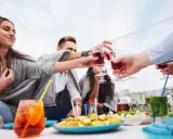 Grupa przyjaciół wznosi toast aperitifem, ciesząc się spotkaniem.