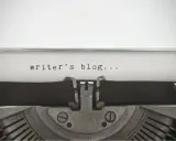 Maszyna do pisania z napisem "writer's blog..." na papierze. Idealny przykład wpisu na bloga po angielsku.