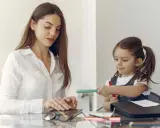 Pedagog specjalny wspiera dziecko w nauce. Kobieta i dziewczynka siedzą przy stole, rysują.