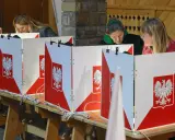 Kobiety głosują w wyborach do sejmu. Kabiny wyborcze ozdobione są godłem Polski.
