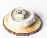 Deliciosa tarta de oro, cubierta de blanco y decorada con chocolate. Presentada sobre una base de madera rústica.
