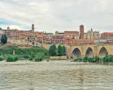 Un pintoresco pueblo con un puente de piedra sobre un río, ideal para visitar si buscas pueblos bonitos cerca de Valladolid.