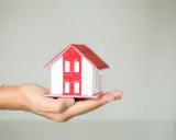 Dłoń trzyma model domu, symbolizując zgodę dożywotnika na sprzedaż nieruchomości.