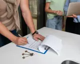 Firma de un contrato de alquiler, quizás un modelo 111 para que sirva de acuerdo. Llaves y portátil presentes.