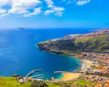 Widok na Funchal, kiedy na Maderę przylatuje samolot. Błękitne morze, plaża, port i zielone wzgórza.