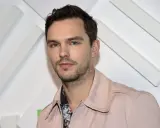 Nicholas Hoult, känd från filmer och tv-program, poserar framför en vit bakgrund med diagonala linjer.