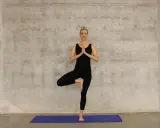 Kvinna i svart träningsklädsel utför trädpositionen, en klassisk yogaövning som passar utmärkt för senior yoga.