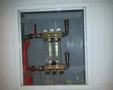 Widoczny zawór RTL na powrocie systemu ogrzewania podłogowego. Metalowa obudowa skrywa skomplikowaną instalację hydrauliczną.