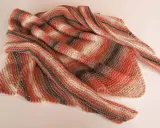 Chal dos agujas tejido a mano con rayas degradadas en tonos naranjas, marrones y blancos. Suave y acogedor, perfecto para cualquier ocasión.