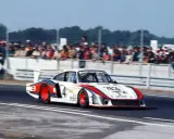 Der Porsche 935 "Moby Dick" rast auf der Rennstrecke, die Zuschauer jubeln.