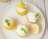 Quatre citrons givrés garnis de crème et de menthe, prêts à être dégustés. Un délice rafraîchissant !
