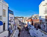 Bunte Gassen in Albufeira, Algarve, mit Geschäften und Restaurants, die sich den Hügel hinaufschlängeln.