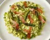 Risotto cremoso con asparagi freschi e croccanti strisce di speck, un piatto primaverile che delizia il palato.
