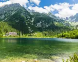 Malownicze Tatry Morskie Oko z krystalicznie czystą wodą, otoczone zielonymi lasami i skalistymi szczytami.