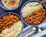 Dos tazones de curry de garbanzos con arroz basmati y pan naan.