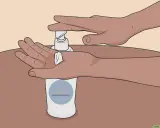 Mani che premono un erogatore di crema idratante per lenire le ascelle irritate. Rimedi naturali efficaci.