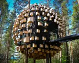 Treehotel Sweden: en sfärisk byggnad täckt av fågelholkar, omgiven av tallskog. En gångbro leder till den unika arkitekturen.