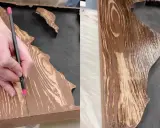 Mano detallando un diseño para pintar efecto madera sobre una superficie.