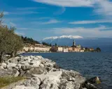 Vista di un borgo sul lago, con montagne innevate sullo sfondo. Perfetto per sapere dove andare 2 giorni in vacanza nord Italia.