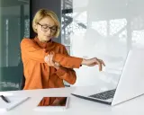 Kobieta z bólem łokcia, zastanawia się, co to jest entezopatia. Siedzi przy biurku z laptopem.