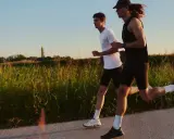 Zwei Männer laufen auf einem Feldweg, die Sonne scheint. Sie wollen schneller laufen und genießen die Abendstimmung.