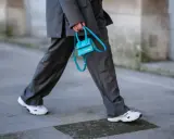 Elegancki damski garnitur w połączeniu z białymi sneakersami i turkusową torebką.