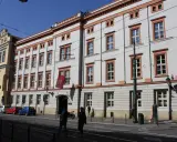 Uniwersytet Papieski w Krakowie, gdzie można studiować różne kierunki. Budynek z czerwonymi akcentami i flagą.