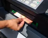 Mano sacando un billete de 50 euros de un cajero automático. La imagen muestra la acción de retirar dinero, lo que nos hace pensar en cuanto dinero se puede sacar del cajero.