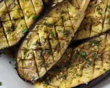 Gegrilltes Gericht mit Aubergine, gewürzt mit Kräutern und Knoblauch.