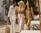 Tre donne passeggiano con stile, mostrando come vestirsi al mare con abiti leggeri e accessori estivi.