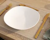 Une assiette blanche est dressée sur un set de table, avec la position des couverts à la française : fourchette à gauche, couteau à droite.