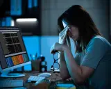 Femme fatiguée devant un écran, lunettes à la main. La hyperconnectivité définition se reflète dans son regard las face aux données.