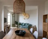 Comedor y sala minimalista para espacios pequeños. Mesa de madera, sillas grises, sofá verde menta y estantería de roble.