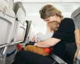 Mama tuli do samolotu z dzieckiem. Siedzą obok siebie, a dziecko bawi się zabawką.